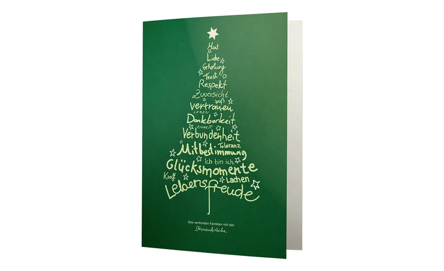 Grüne Karte mit einem Tannenbaum aus Worten wie "Liebe", "Vertrauen" und "Lebensfreude", gestaltet als Sterne und Schriftzüge.